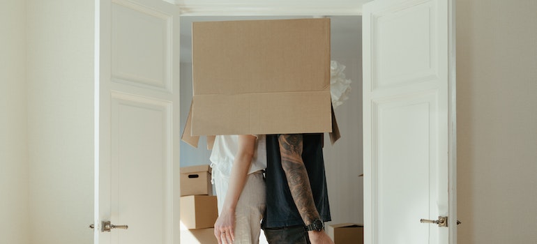 A couple with a cardboard box over their heads, representing the search for reliable interstate moving companies