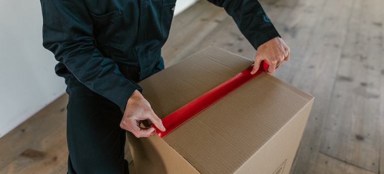 A professional long distance mover packing a cardboard box
